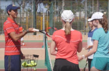 Thumbnail Trainer und internationale Teilnehmer beim Verbessern der Tennis-Techniken